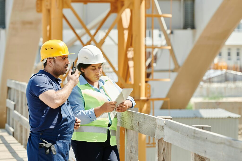 Contractor and clients reviewing house blueprints at a construction site in Chennai